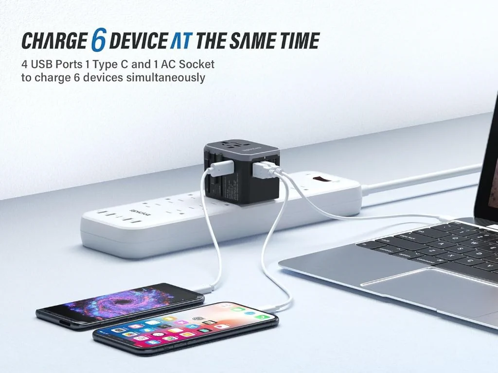 Multi-port universal travel adapter on a power strip charging laptop and phones.
